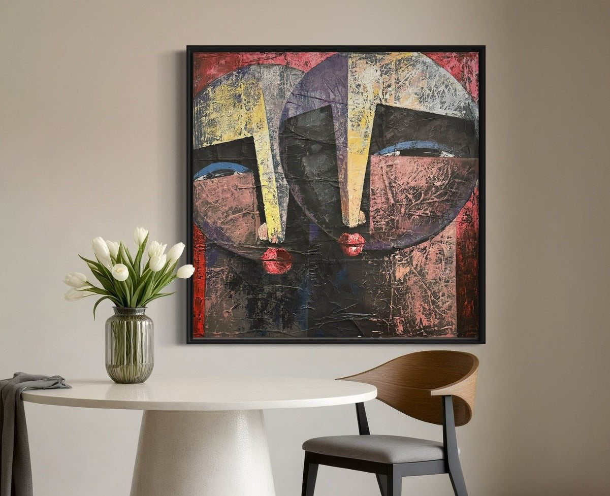 A modern dining area features a round white table, a dark wooden chair, a vase of white tulips, and “Eye Contact”—a textured acrylic painting of two stylized faces by Nigerian artist Christopher Ankeli.