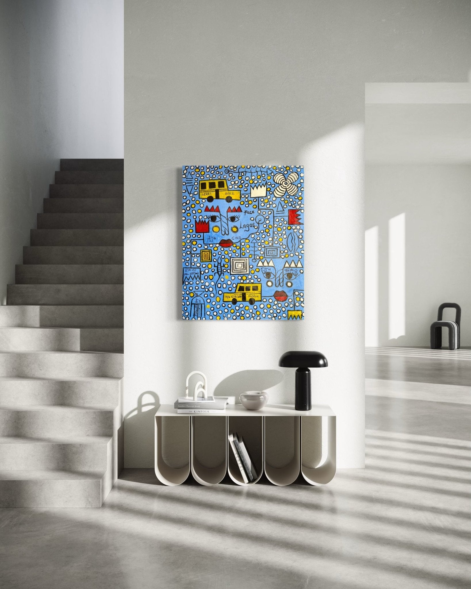 A modern, minimalist interior includes a staircase, a curved white console table with decor, and "Face Of Lagos" by Kolawale Niyi—an abstract painting in blue, yellow, and white—hanging on a light gray wall bathed in sunlight from the right.