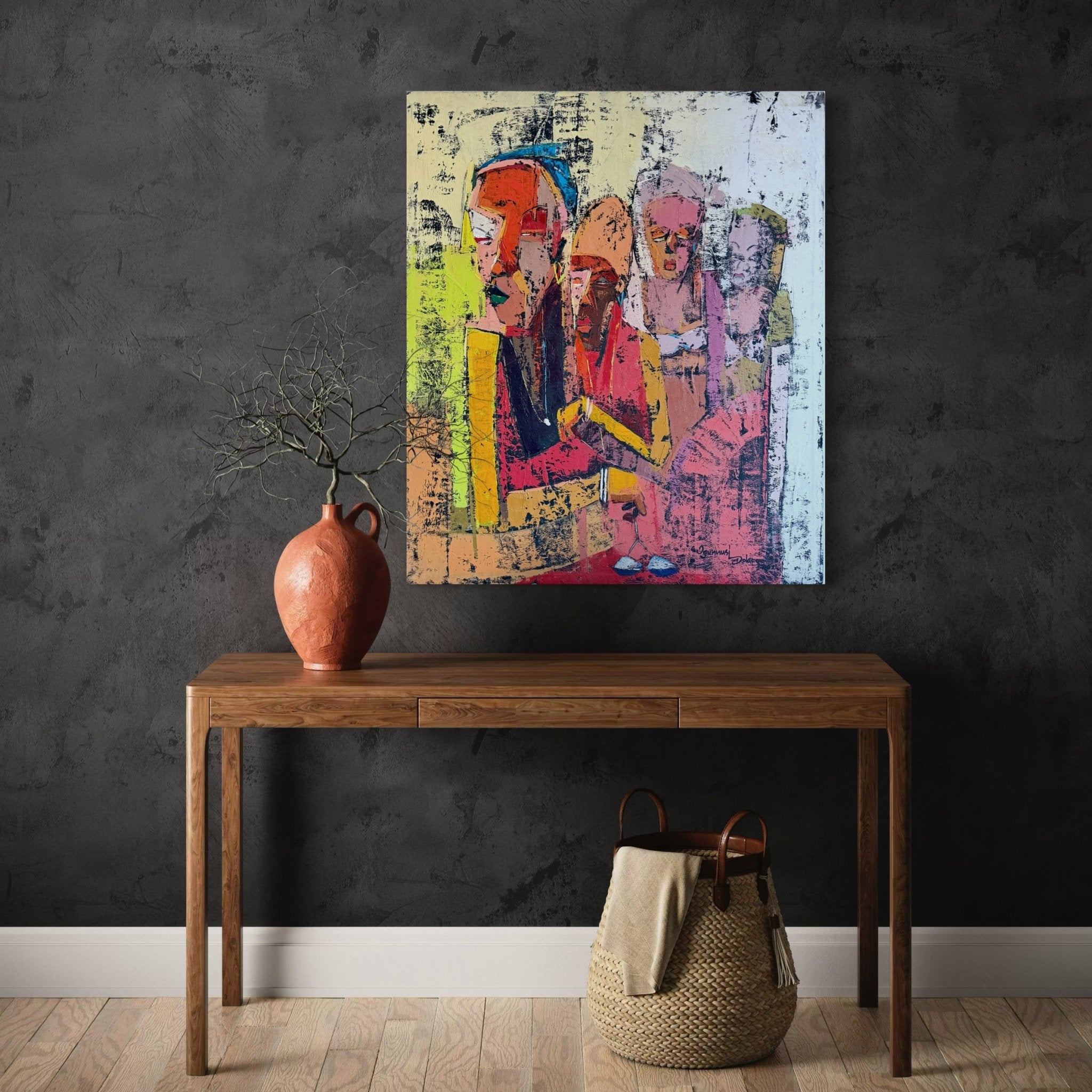 A minimalist room with a dark textured wall, wooden table, orange vase, woven basket, and "Gender Equality" by Dolapo Ogunnusi—hand-signed artwork of four people above the table, includes certificate of authenticity.