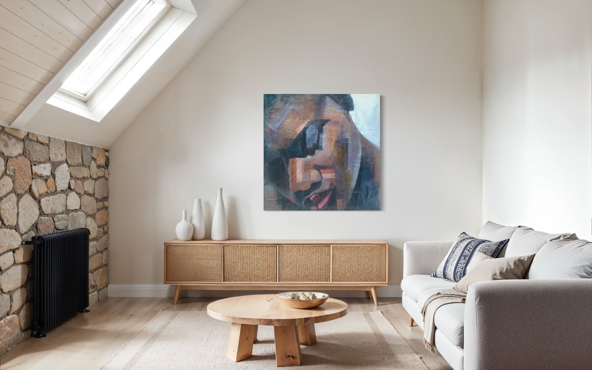 A modern living room features a light sofa, round wooden coffee table, sideboard with vases, stone accent wall, skylight, and “Peace” Textured Painting by Christopher Ankeli—a unique abstract portrait acrylic on canvas—on the wall.