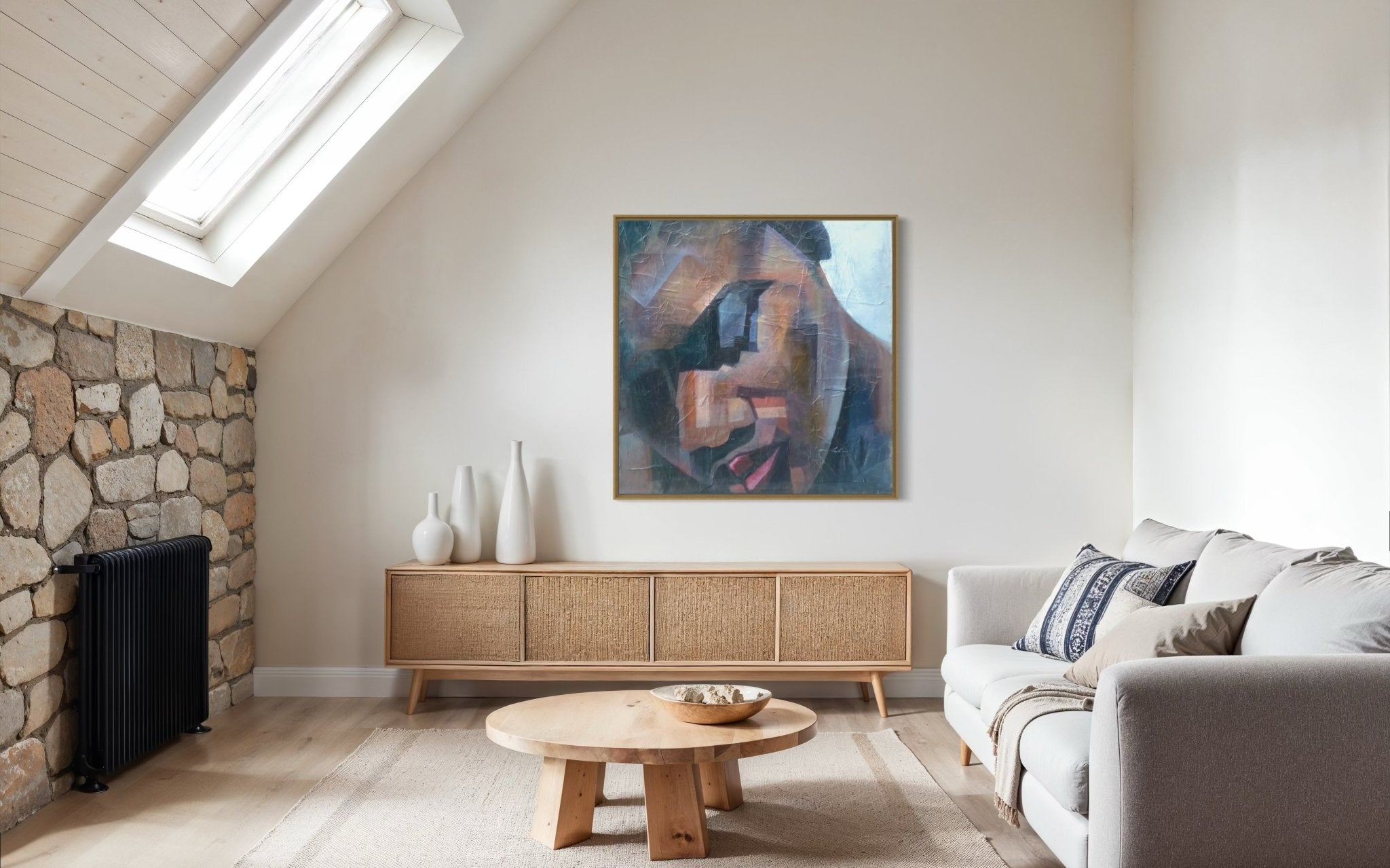 A modern living room with a light sofa, round wooden table, sideboard with vases, and "Peace" Textured Painting by Christopher Ankeli—an abstract acrylic artwork—on the wall under a skylight beside a stone accent wall.