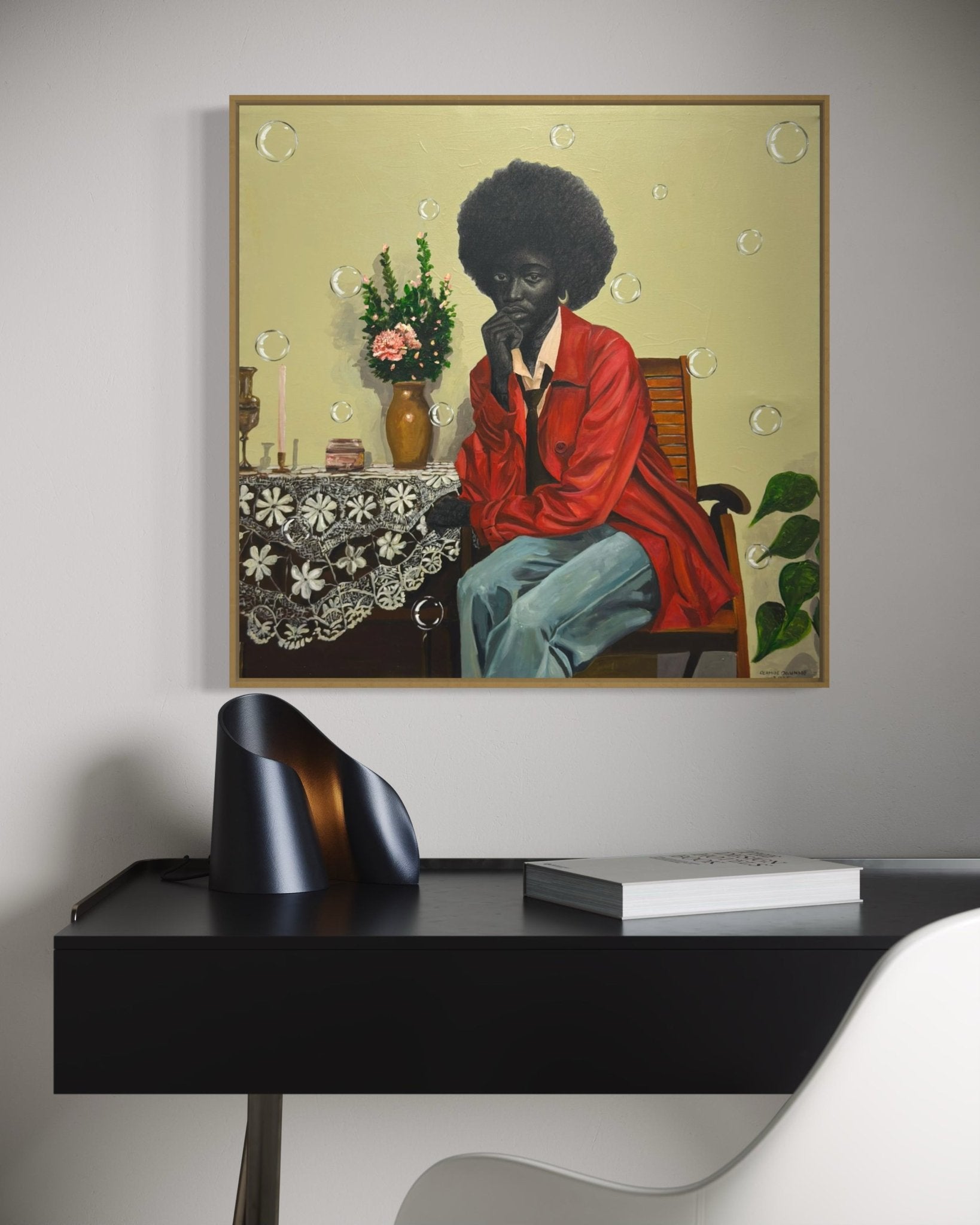 The Presence Of Silence" by Olamide Ogunade, a contemporary African artist, depicts a thoughtful figure with an afro. The framed artwork hangs above a modern black desk with sculptural objects in this minimalist room.