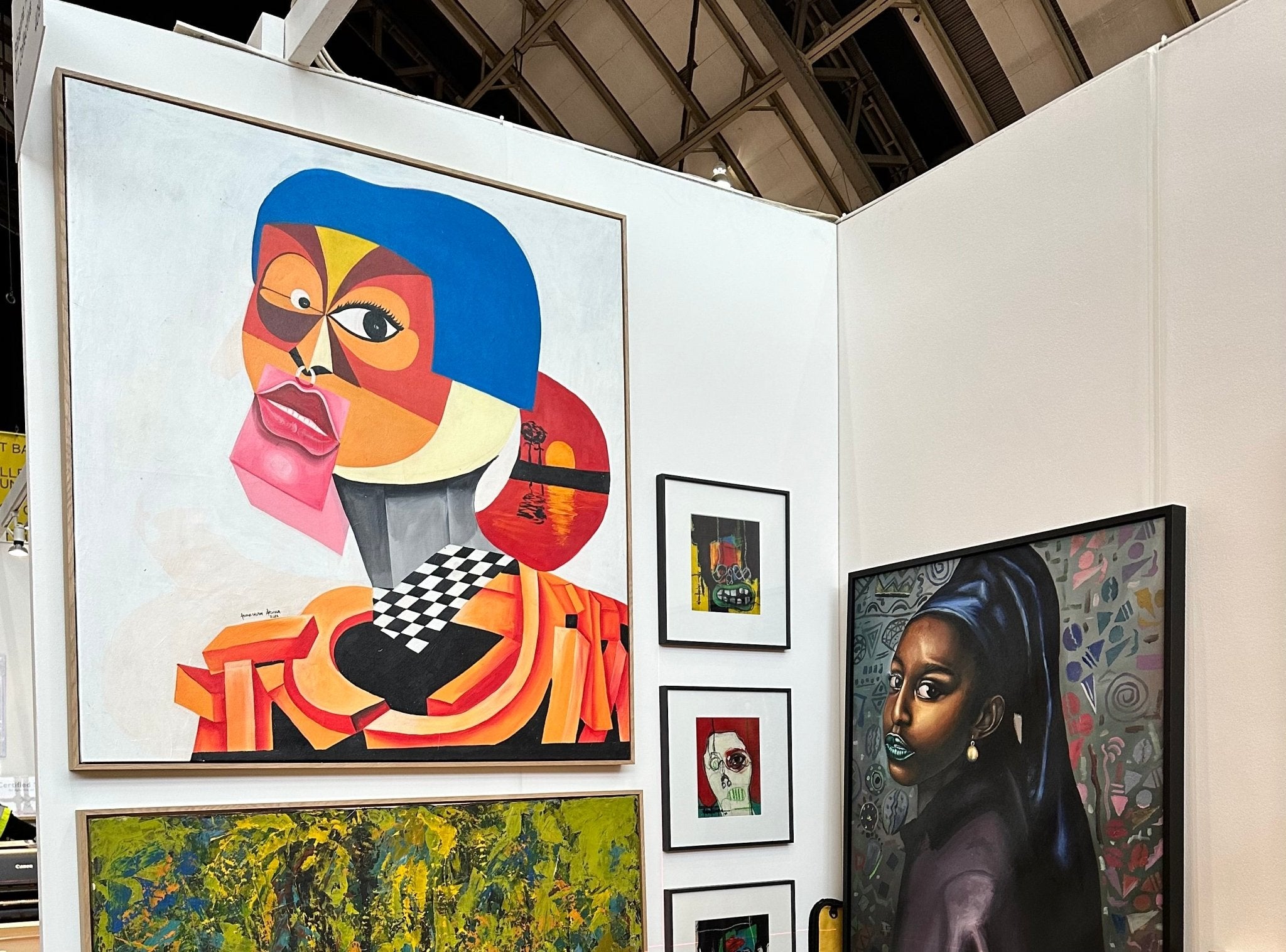 A gallery wall of modern African art by Abiola Abdulsalam, featuring ‘Tranquil Night’ (126 x 120cm), cubist-inspired faces, smaller framed abstracts, and a striking portrait of a woman with blue lipstick on the right.