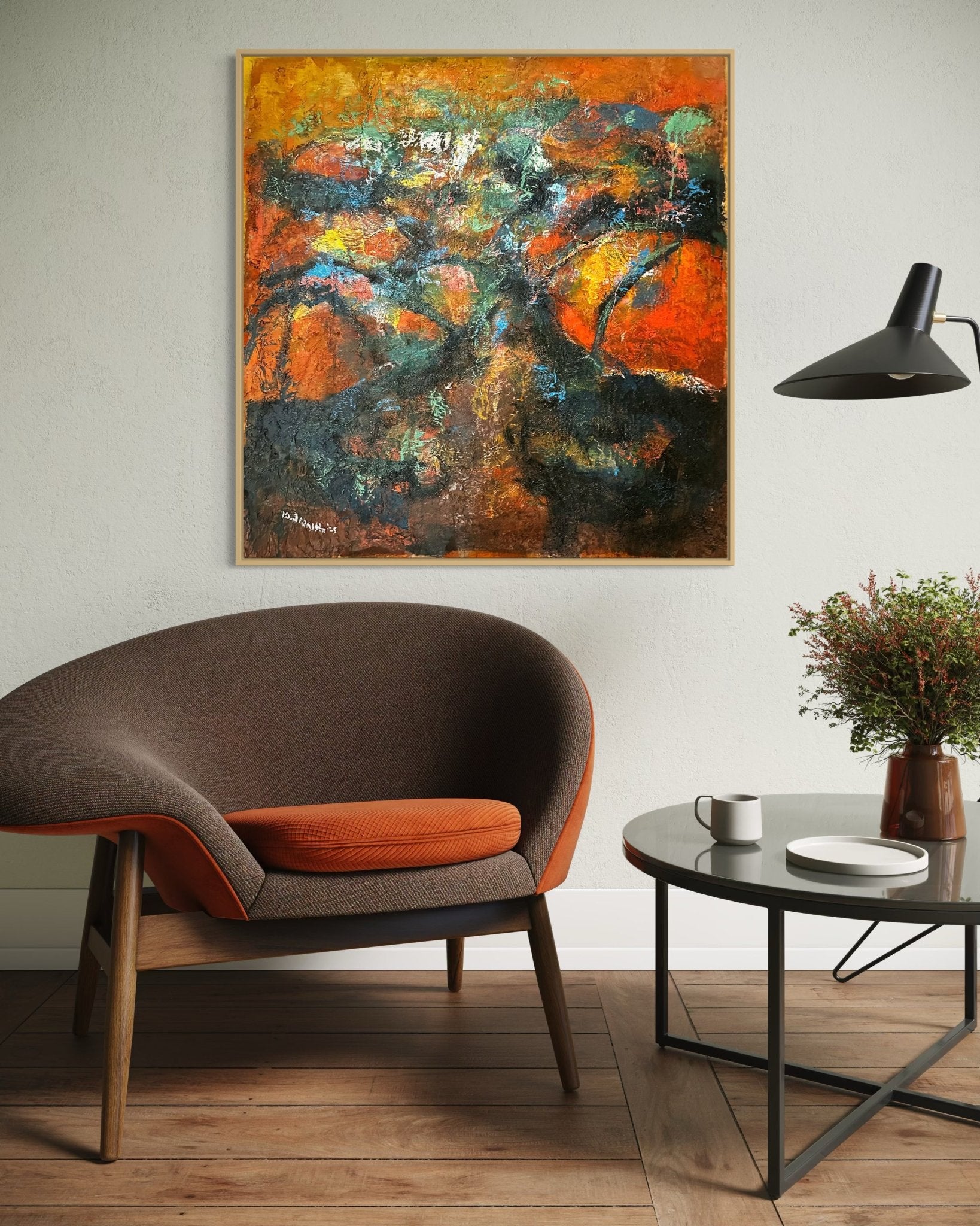 A modern living room with a brown chair and orange cushion, round glass coffee table with flowers, black wall lamp, and unique “Tree Of Life” artwork by Bibianna African Art Collective—hand-signed and comes with certificate of authenticity.