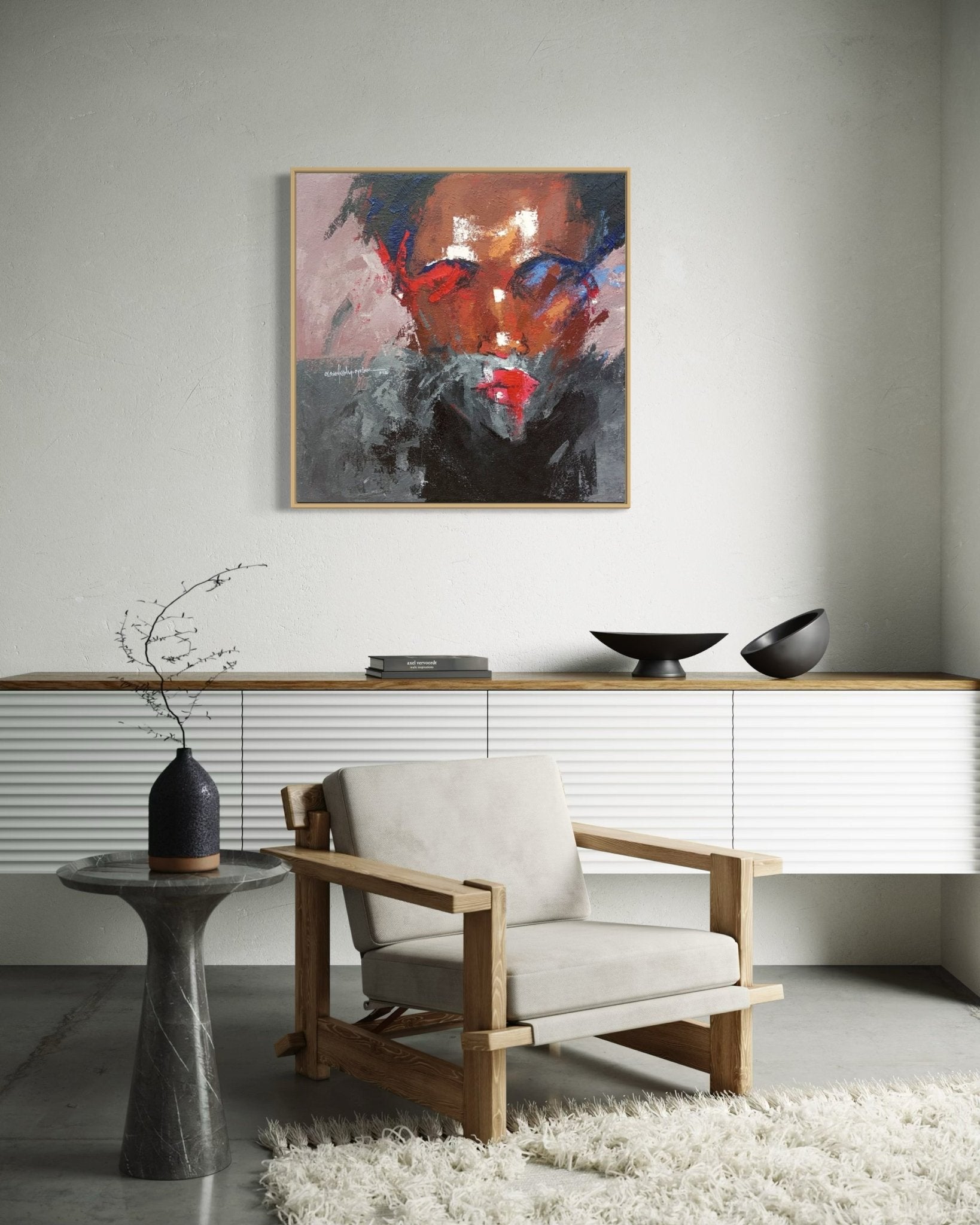 Minimalist living room with a wooden armchair, side table with a vase, white rug, low cabinet, and "Where I Am" (93 x 93cm) by Olasunkanmi Oyelusi hanging above the cabinet as a unique artwork centerpiece.